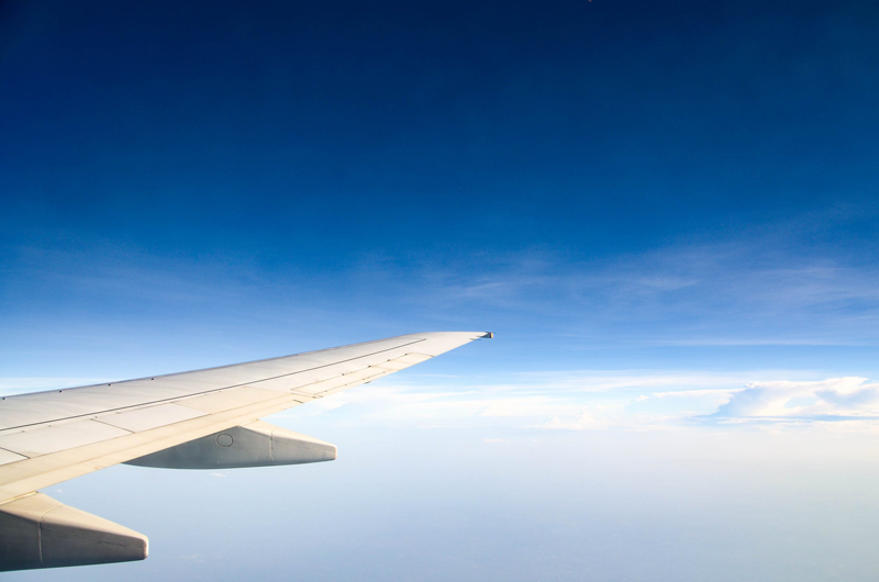 wing of a plan, flying in a blue sky with low clouds
