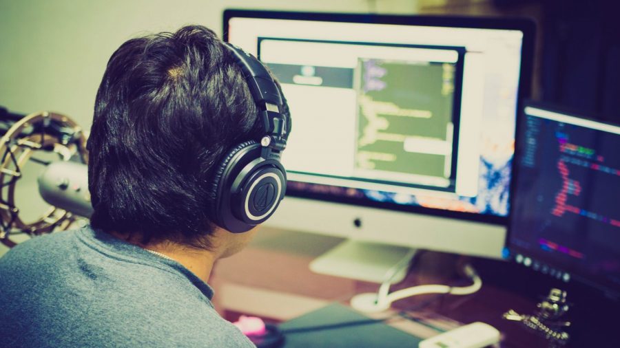 person wears headphones and sits at a computer