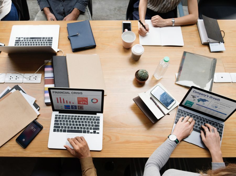 many people working with laptops, date books and drinks at a group table