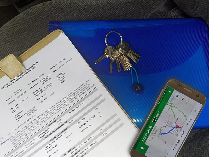 Inspection clipboard with plastic binder, keys and phone with location directions map